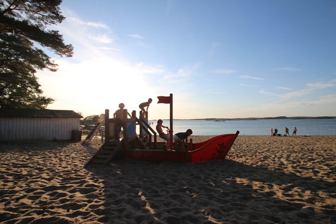 Lekande barn i solnedgången Skepp på stranden